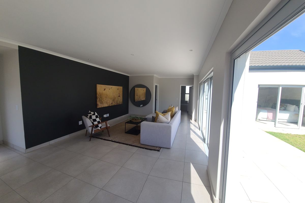Spacious living room featuring large format floor tiles, a dark accent wall, and expansive sliding glass doors providing seamless access to the outdoor area.