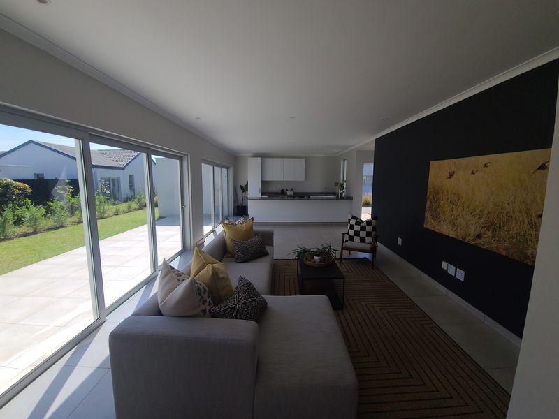 Spacious open-plan living area featuring modern kitchen cabinetry, large sliding glass doors leading to the patio, and a striking black accent wall.
