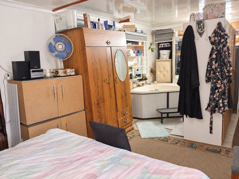 A bedroom featuring an integrated corner bathtub area, carpeted flooring, and a glossy ceiling finish with visible electrical wiring.