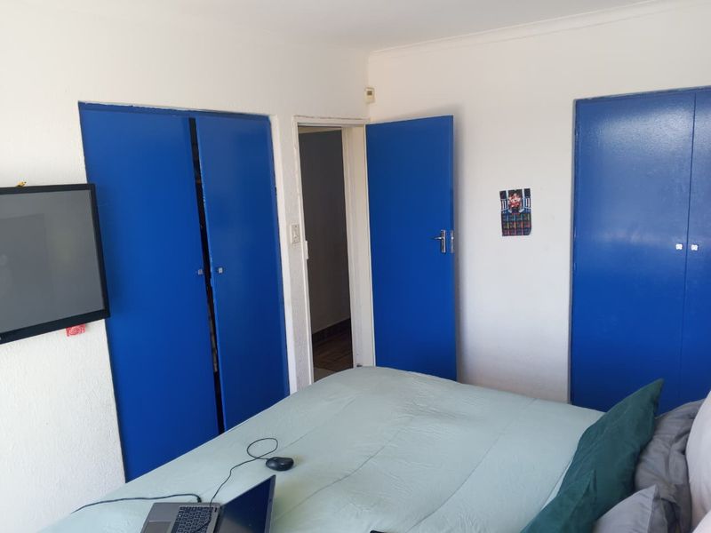 A bedroom featuring built-in cupboards with blue painted doors and standard interior finishes.