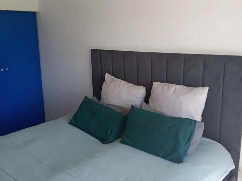 A bedroom featuring a built-in cupboard with a blue door and neutral wall finishes.