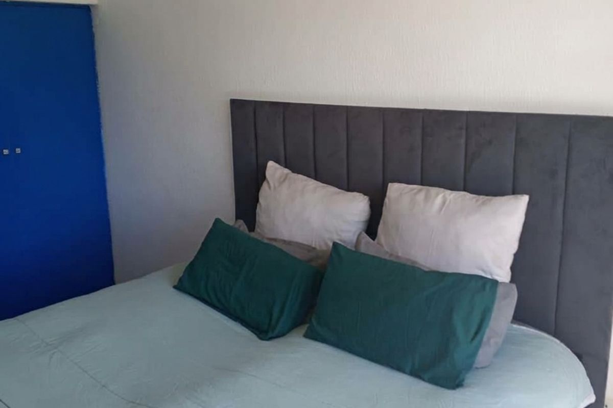 A bedroom featuring a built-in cupboard with a blue door and neutral wall finishes.
