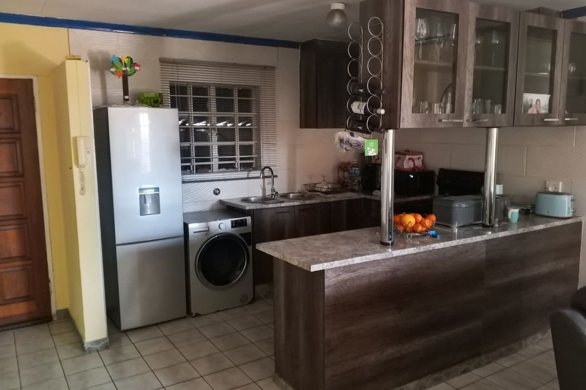 A functional kitchen featuring dark wood-look cabinetry, a breakfast bar, stone-effect countertops, and tiled flooring, providing a practical layout for daily use.