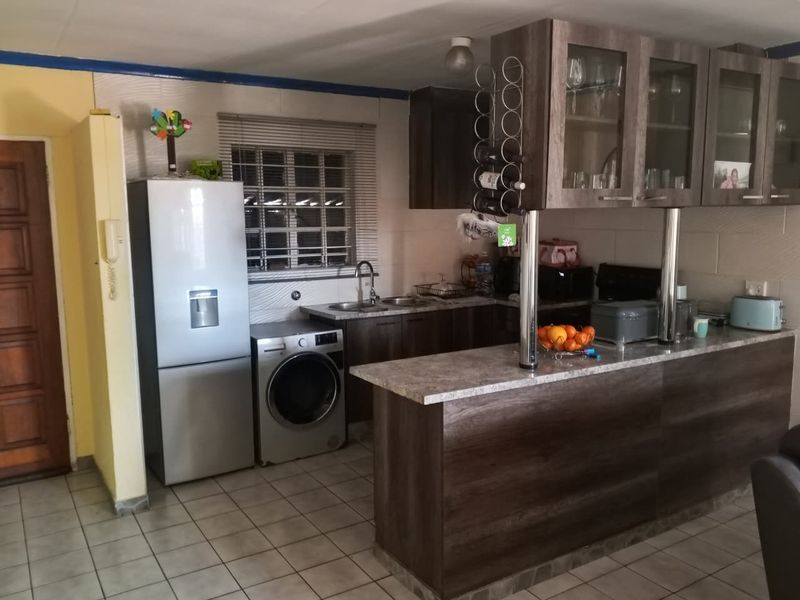 A functional kitchen featuring dark wood-look cabinetry, a breakfast bar, stone-effect countertops, and tiled flooring, providing a practical layout for daily use.