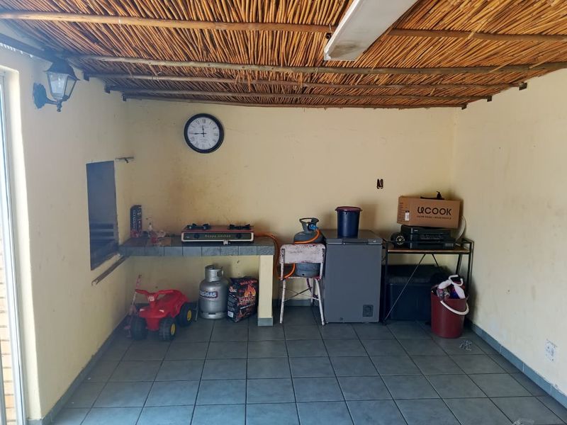 Covered patio area featuring a thatched roof, tiled flooring, and a built-in masonry counter, suitable for outdoor entertaining or a summer kitchen setup.