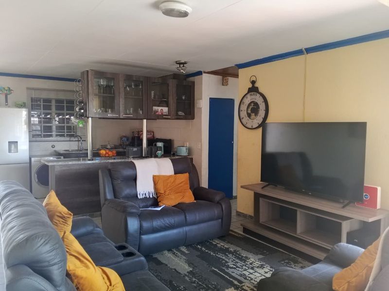 Open-plan living area featuring a compact kitchen with granite countertops and cabinetry, seamlessly flowing into the lounge space.