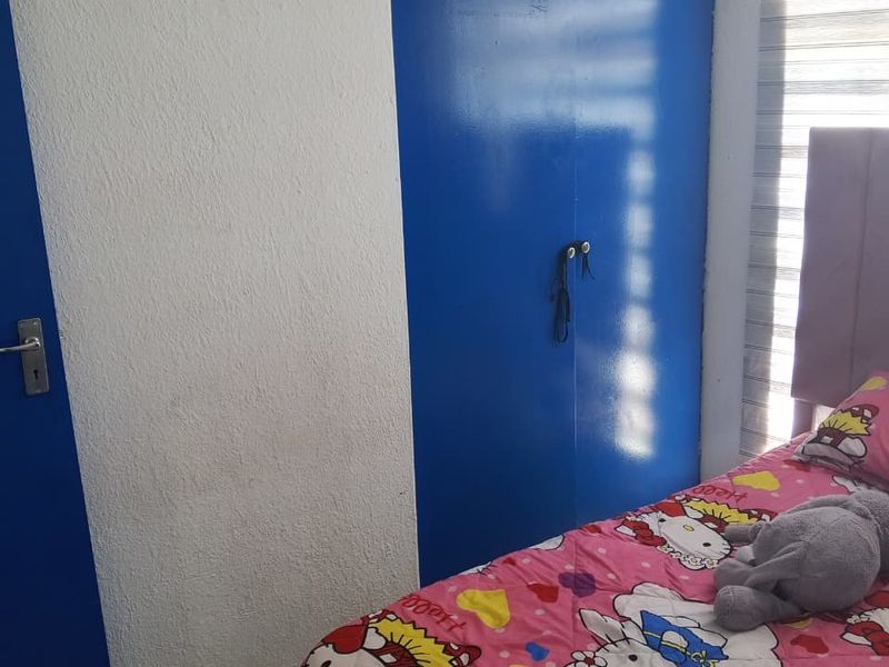 A bedroom featuring built-in blue cupboards, tiled flooring, and modern roller blinds, providing a functional and practical living space.