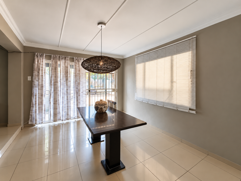 A bright dining room featuring polished tiled flooring, a modern pendant light, and large sliding glass doors leading to the exterior.
