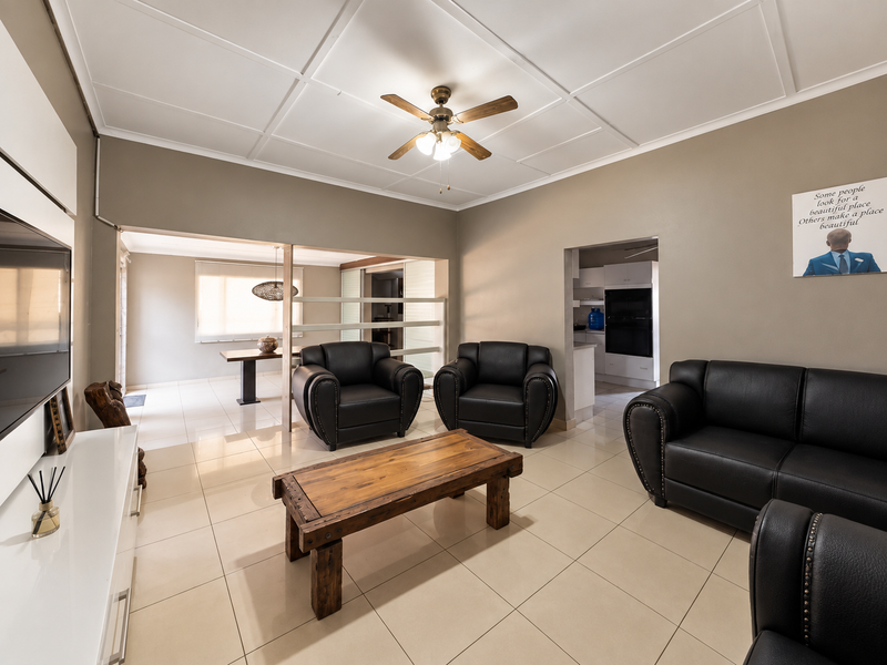 Spacious open-plan living area featuring tiled floors, a ceiling fan, and a seamless transition to the kitchen and dining space.