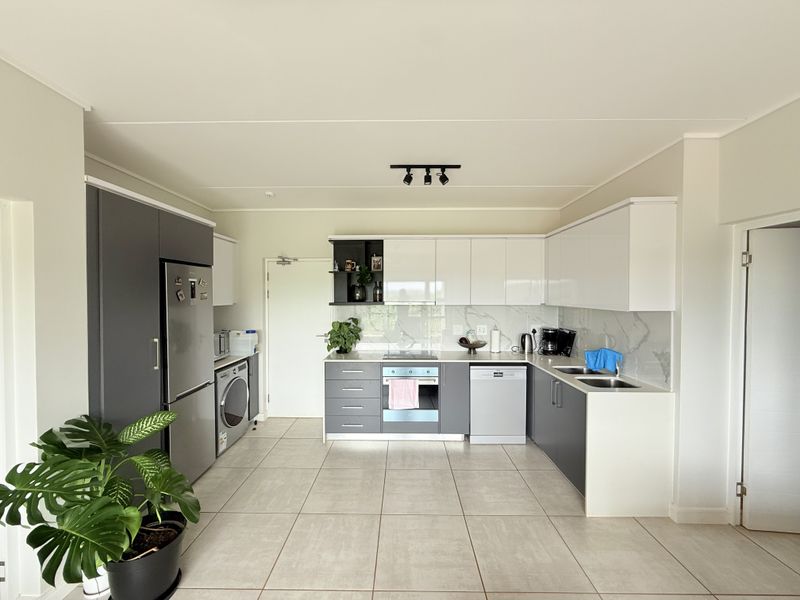 Modern kitchen featuring two-tone cabinetry, marble-look backsplash, integrated oven, hob, and tiled flooring in an open-plan layout.