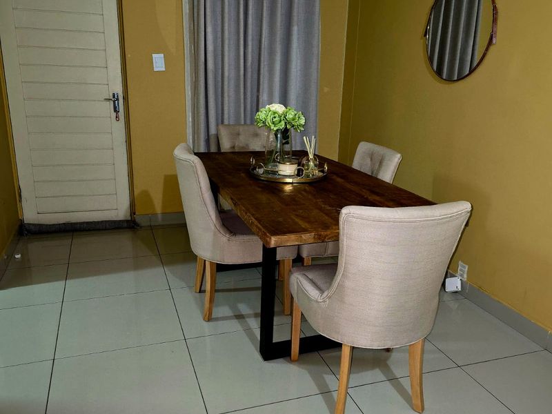 A dining area featuring large format floor tiles, crown molding, and neutral wall finishes, providing a functional space for meals.