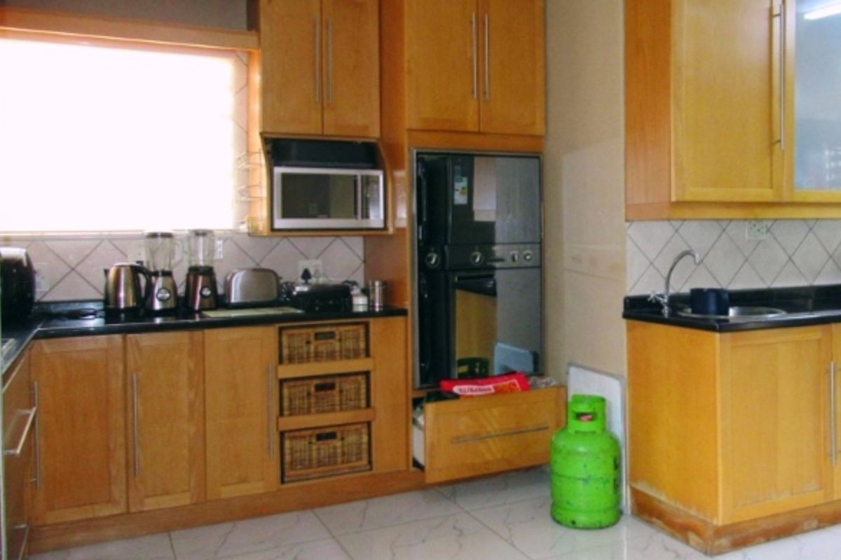 A functional kitchen featuring wooden cabinetry, granite countertops, built-in oven and microwave, and tiled flooring.