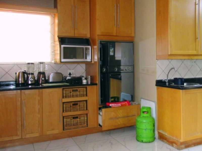 A functional kitchen featuring wooden cabinetry, granite countertops, built-in oven and microwave, and tiled flooring.