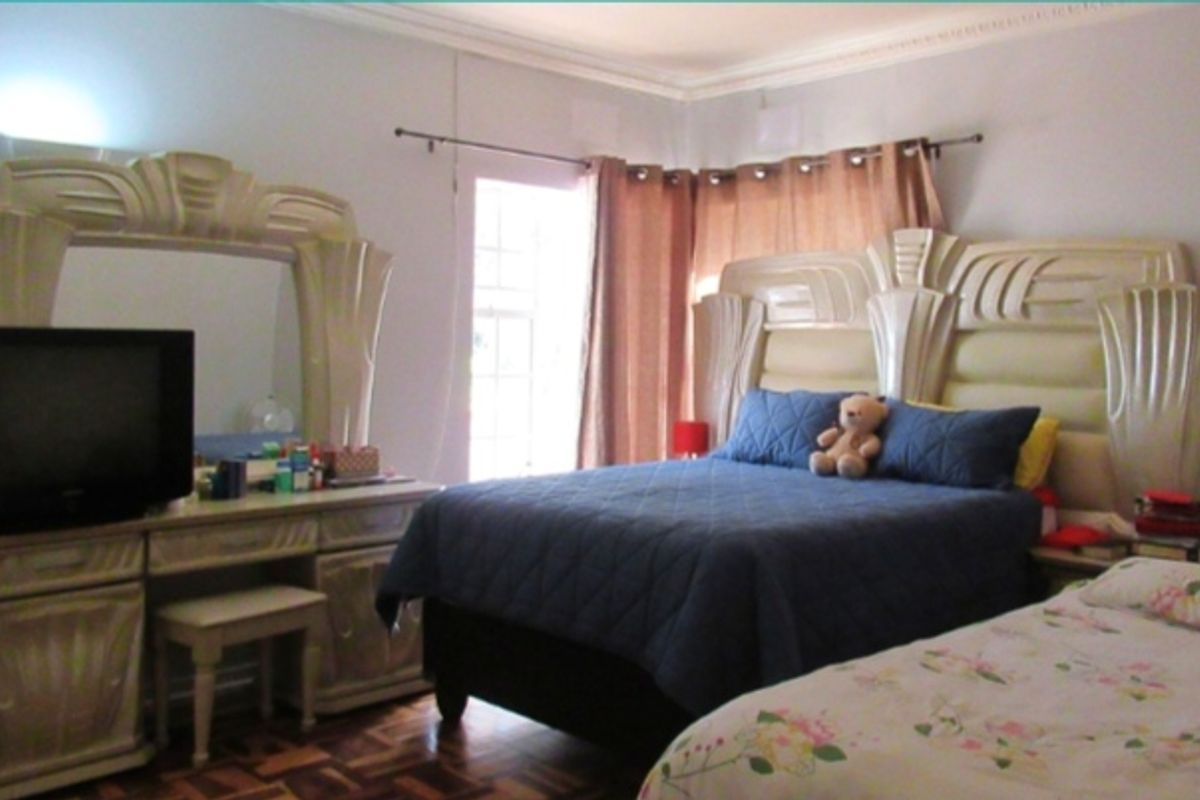 A bedroom featuring parquet flooring and decorative crown molding, with access to natural light through a window.