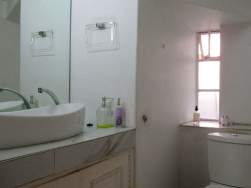 A functional bathroom featuring a vessel sink on a vanity cabinet, a wall-mounted mirror, and a standard toilet with natural light from a window.