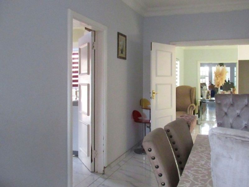 A view of a living area featuring tiled flooring and coved ceilings, with doorways leading to adjacent rooms.