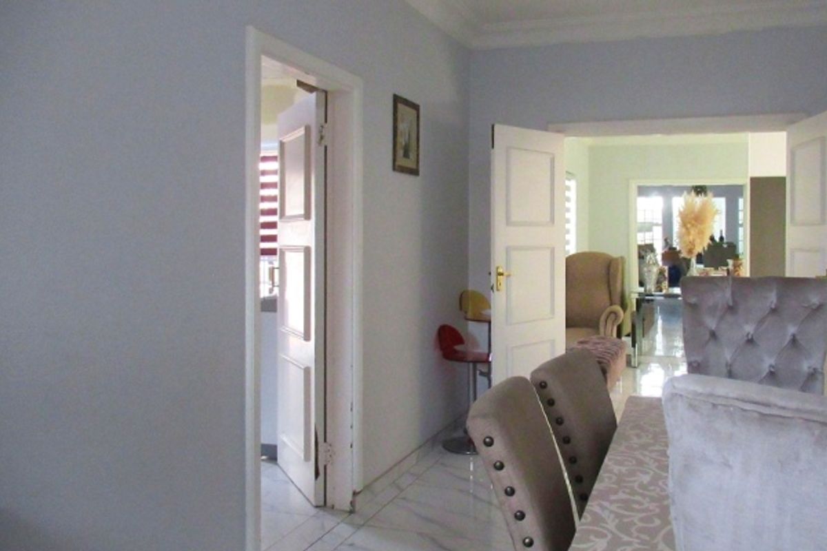 A view of a living area featuring tiled flooring and coved ceilings, with doorways leading to adjacent rooms.
