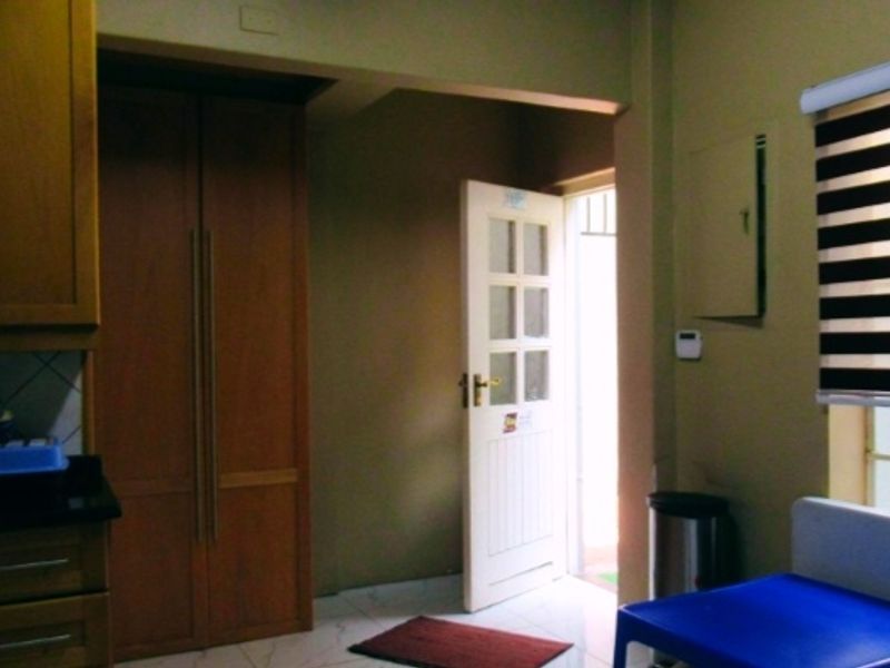A functional scullery area featuring built-in wooden cabinetry, tiled flooring, and direct access to an exterior space.