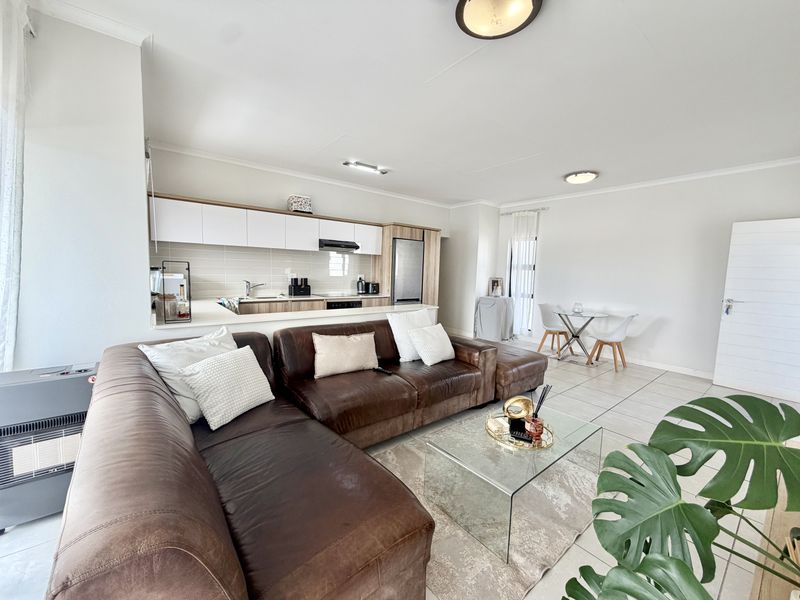 Spacious open-plan living area featuring a modern kitchen with built-in cabinetry, tiled floors, and a seamless flow to the dining and lounge space.