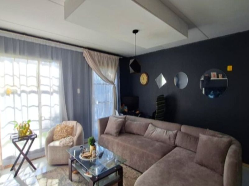 A living room featuring a dropped ceiling bulkhead, pendant lighting, and large sliding glass doors providing natural light.