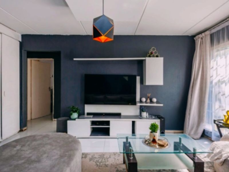 A modern living room featuring a dark accent wall, built-in media cabinetry with floating shelves, and a recessed ceiling detail.