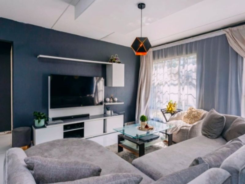 A well-maintained living room featuring a built-in media console, floating shelving, and modern pendant lighting, creating a comfortable and functional living space.