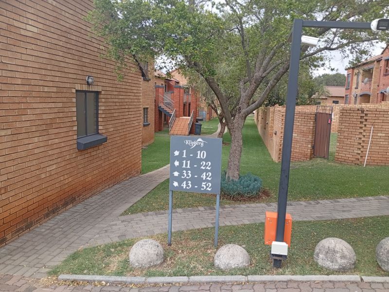Exterior view of the townhouse complex entrance featuring brick facades, paved walkways, and clear directional signage for the residential units.