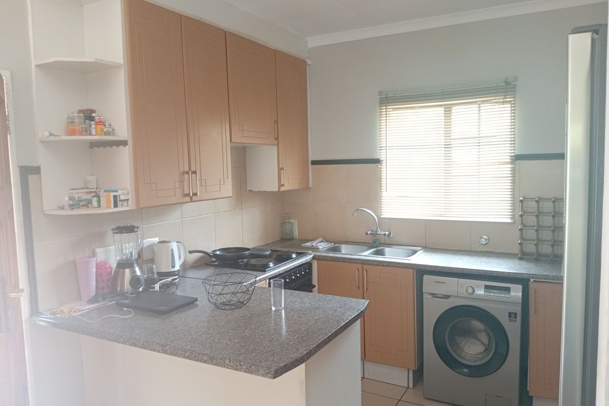 A functional kitchen featuring laminate cabinetry, granite-look countertops, a double bowl sink, and tiled splashbacks, offering a practical layout for daily use.