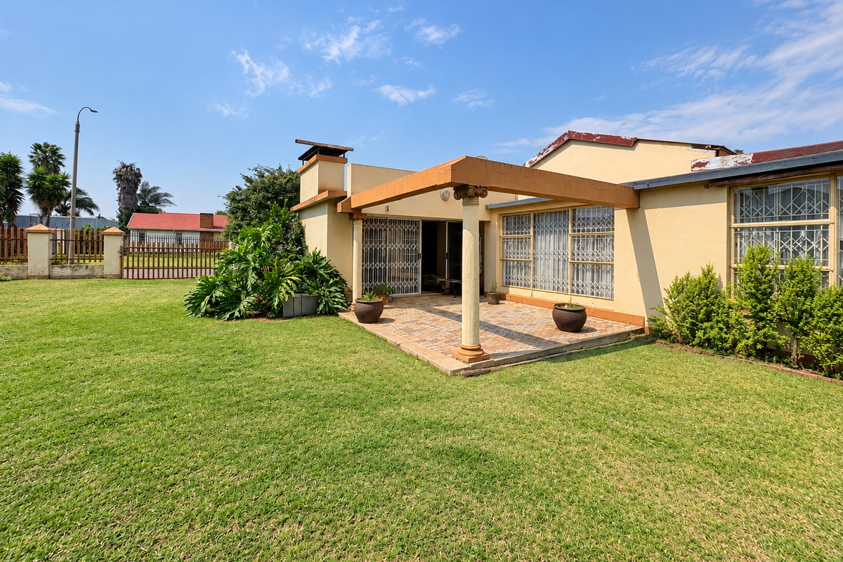 Rear view of the property featuring a paved patio area with a covered pergola, security gates, and a spacious garden.