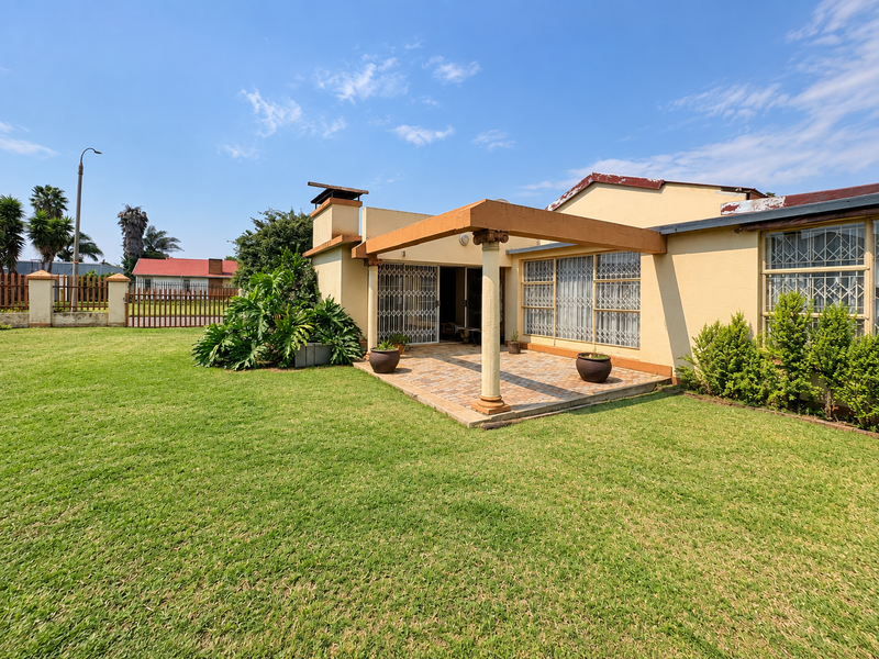 Rear view of the property featuring a paved patio area with a covered pergola, security gates, and a spacious garden.