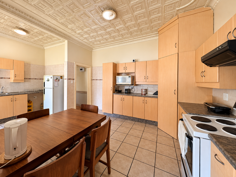 Spacious kitchen featuring light wood cabinetry, tiled flooring, decorative ceiling tiles, and integrated appliances, offering a functional layout with ample storage space.
