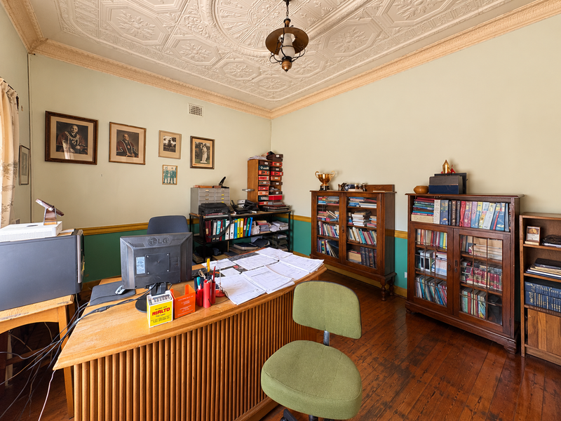 A home office featuring a classic ornate pressed metal ceiling, timber flooring, and traditional picture rails, offering a character-filled workspace.