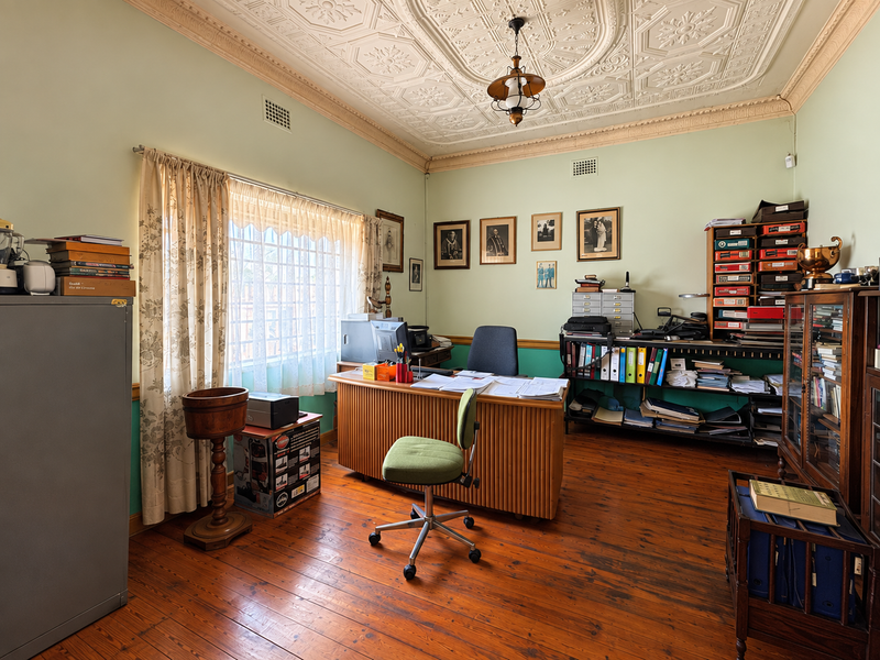 A home office featuring original pressed metal ceilings, decorative cornices, and polished timber flooring, offering a classic character aesthetic.