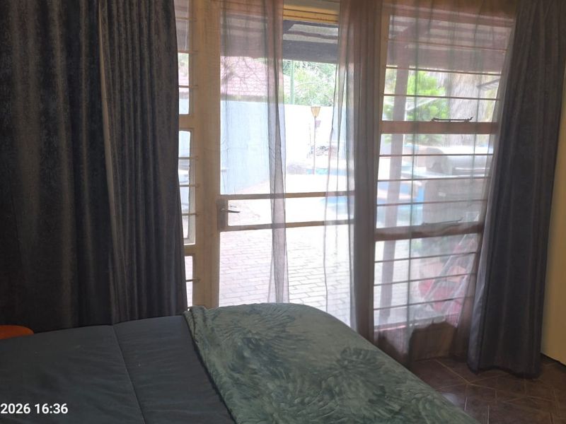Bedroom featuring tiled flooring, a built-in wardrobe, and direct access to an outdoor patio area through sliding glass doors.