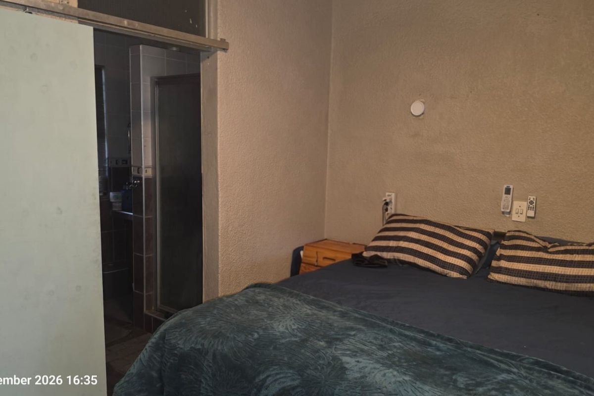 A bedroom featuring textured walls and a sliding door leading to an adjacent bathroom area.