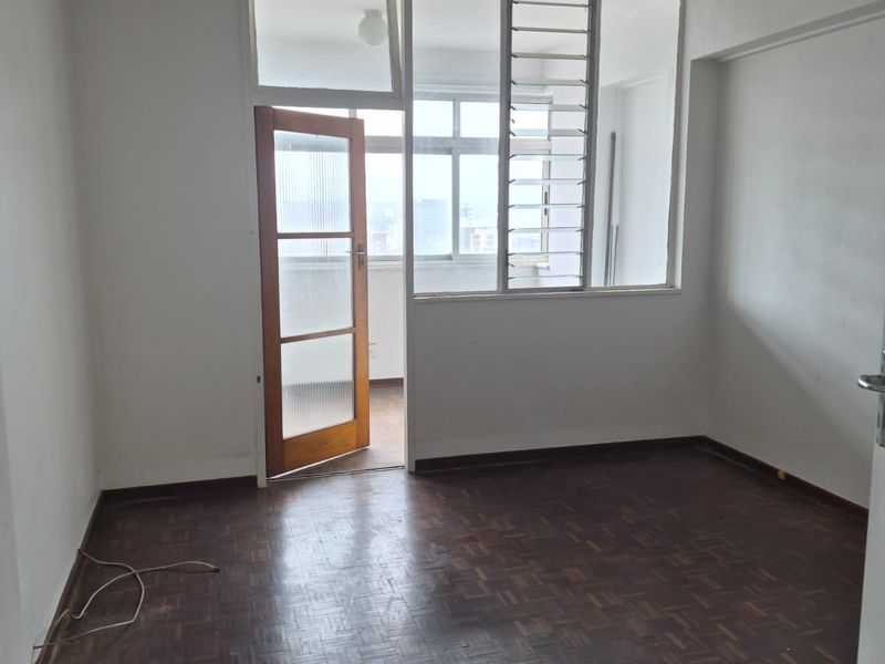 An empty bedroom featuring original parquet flooring, a timber-framed door, and access to an adjoining balcony area.