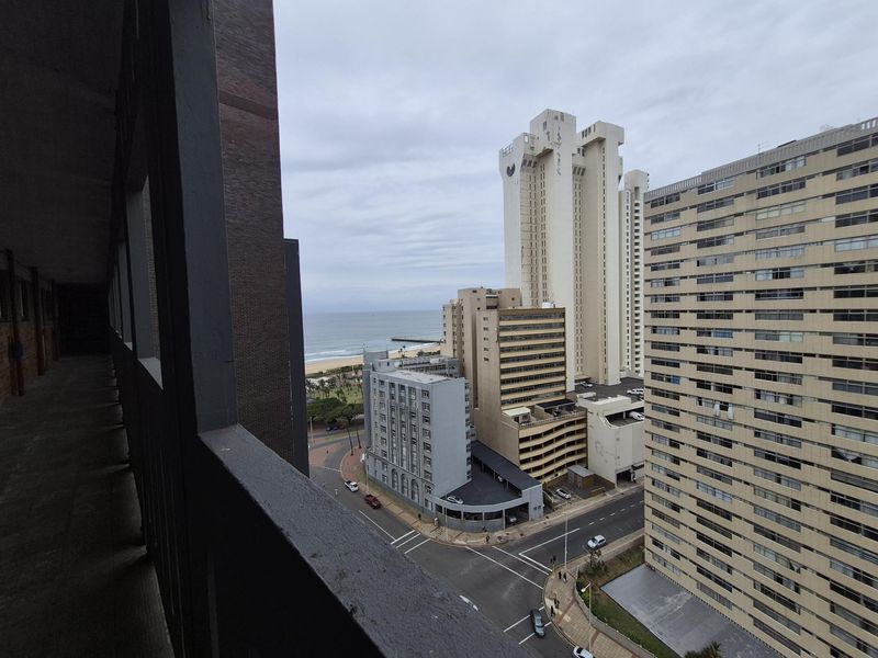 An elevated urban view overlooking the surrounding city skyline, street intersection, and distant coastline.