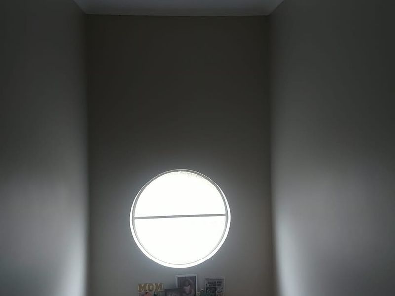 A narrow hallway space featuring a distinctive circular window and modern track lighting, providing a unique architectural focal point.