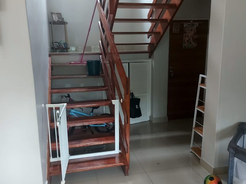Entrance hallway featuring a wooden staircase, tiled flooring, and a built-in storage cupboard, providing access to the main living area.