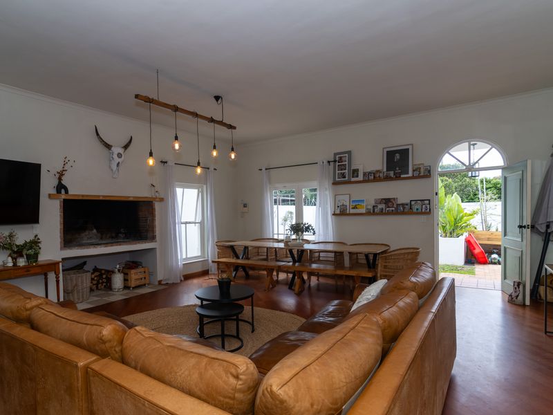 Spacious open-plan living and dining area featuring a built-in fireplace, timber flooring, and direct access to the outdoor patio through an arched doorway.