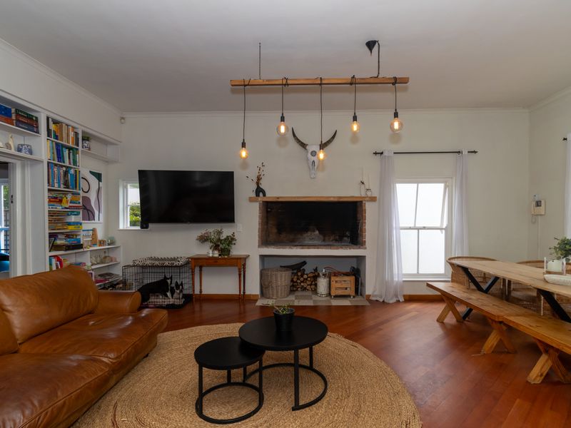 Open plan living and dining area featuring timber flooring, a built-in fireplace, and custom built-in shelving.