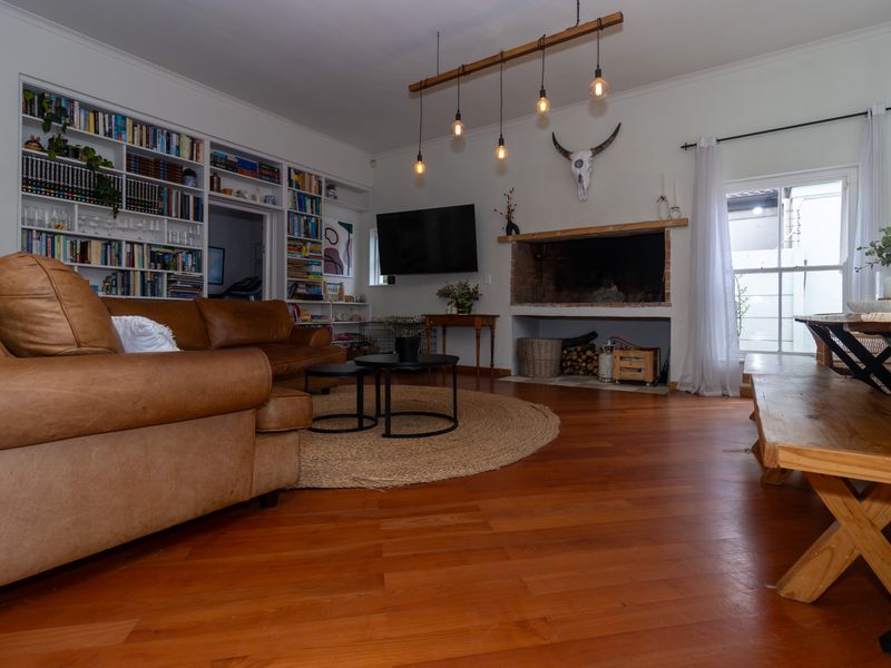 Spacious living room featuring warm timber flooring, a large built-in bookshelf, and a traditional fireplace, creating a cozy and inviting atmosphere.