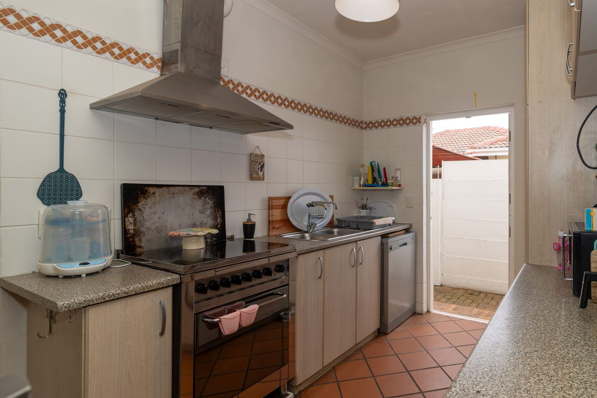 A functional kitchen featuring laminate cabinetry, a stainless steel extractor fan, a freestanding stove, and direct access to an outdoor area.