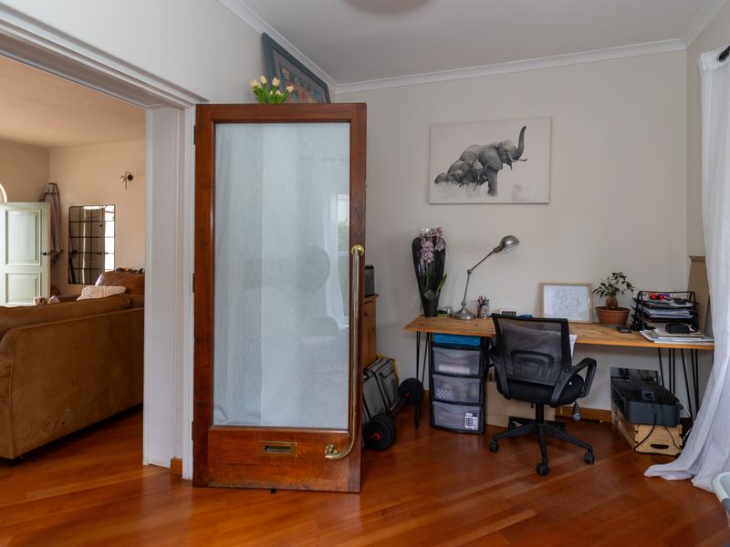 A functional home office space featuring polished hardwood flooring and a classic timber door, providing a quiet area for work or study.