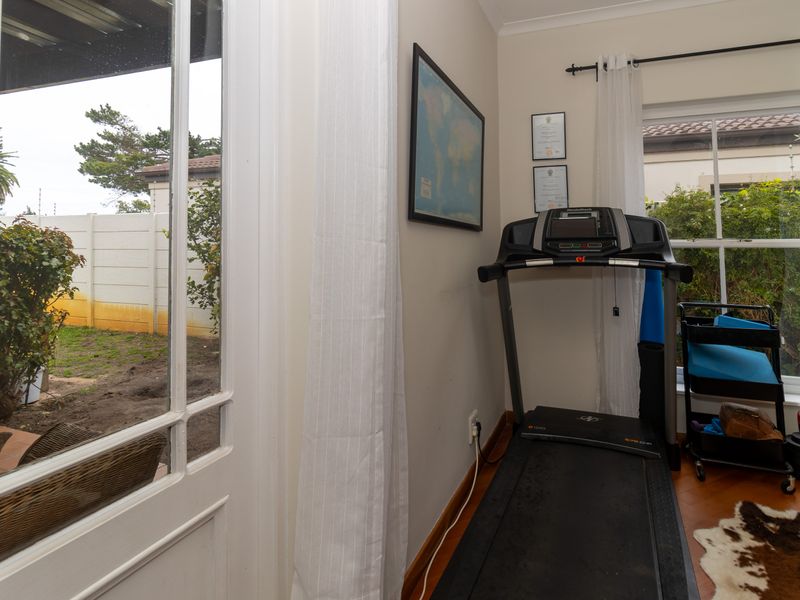 A functional gym space featuring parquet flooring, coved ceilings, and direct access to the rear garden through a glass-paneled door.