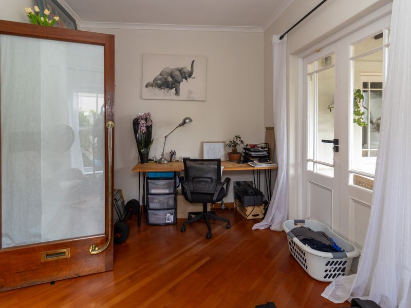 A bright home office featuring polished hardwood flooring and classic french doors providing direct access to the outdoor area.