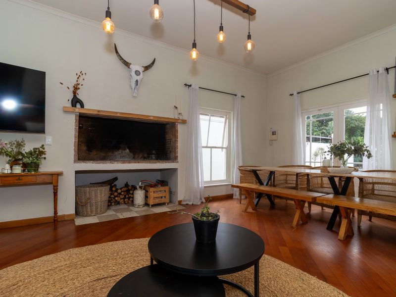 Spacious living area featuring warm hardwood flooring, a large built-in fireplace, and natural light through sash windows and french doors leading outdoors.