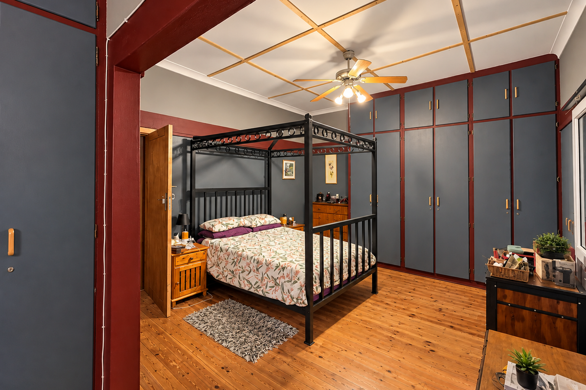 Spacious bedroom featuring extensive floor-to-ceiling built-in cabinetry, polished timber flooring, and a decorative ceiling with a central fan.