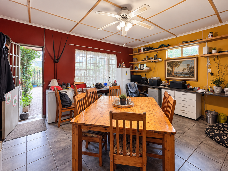 Open plan dining and utility area featuring tiled flooring, built-in cabinetry, and a ceiling fan, with direct access to an outdoor patio area.