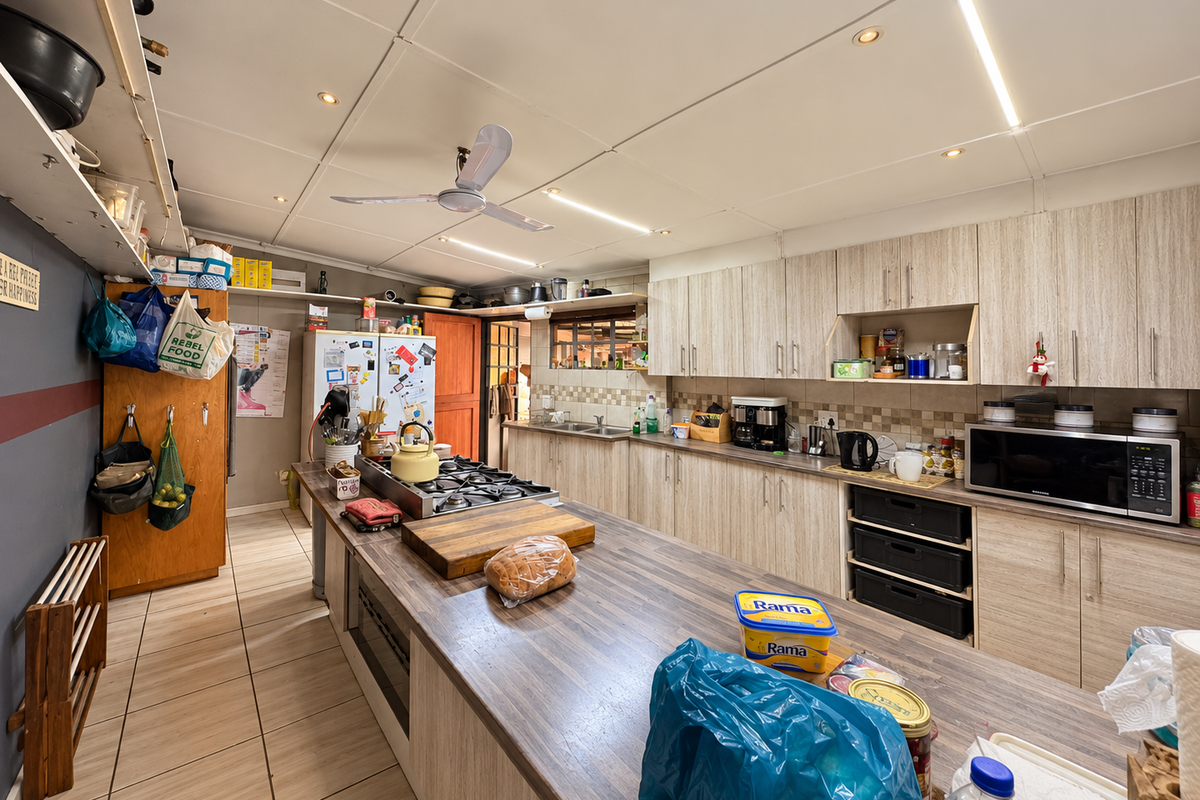 Spacious kitchen featuring extensive built-in cabinetry, a large central island with a gas hob, and tiled flooring throughout.